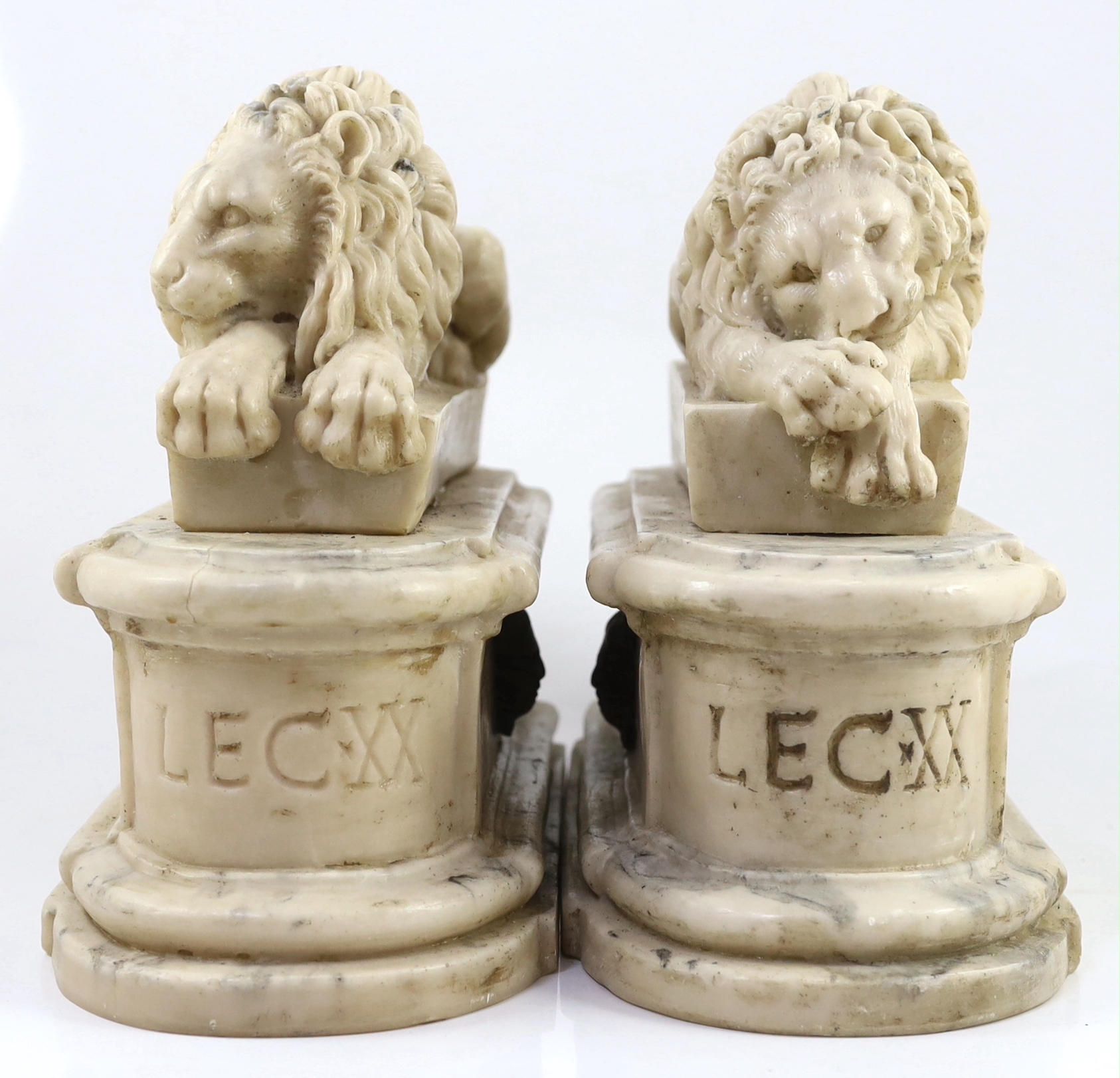 After the Antique. A pair of marble resin models of the Medici lions, each seated upon an oblong plinth, applied with bronze masks, inscribed LECXX, 41cm long, 15cm deep, 29cm high